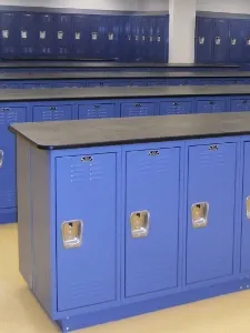 A row of blue lockers in front of a wall.